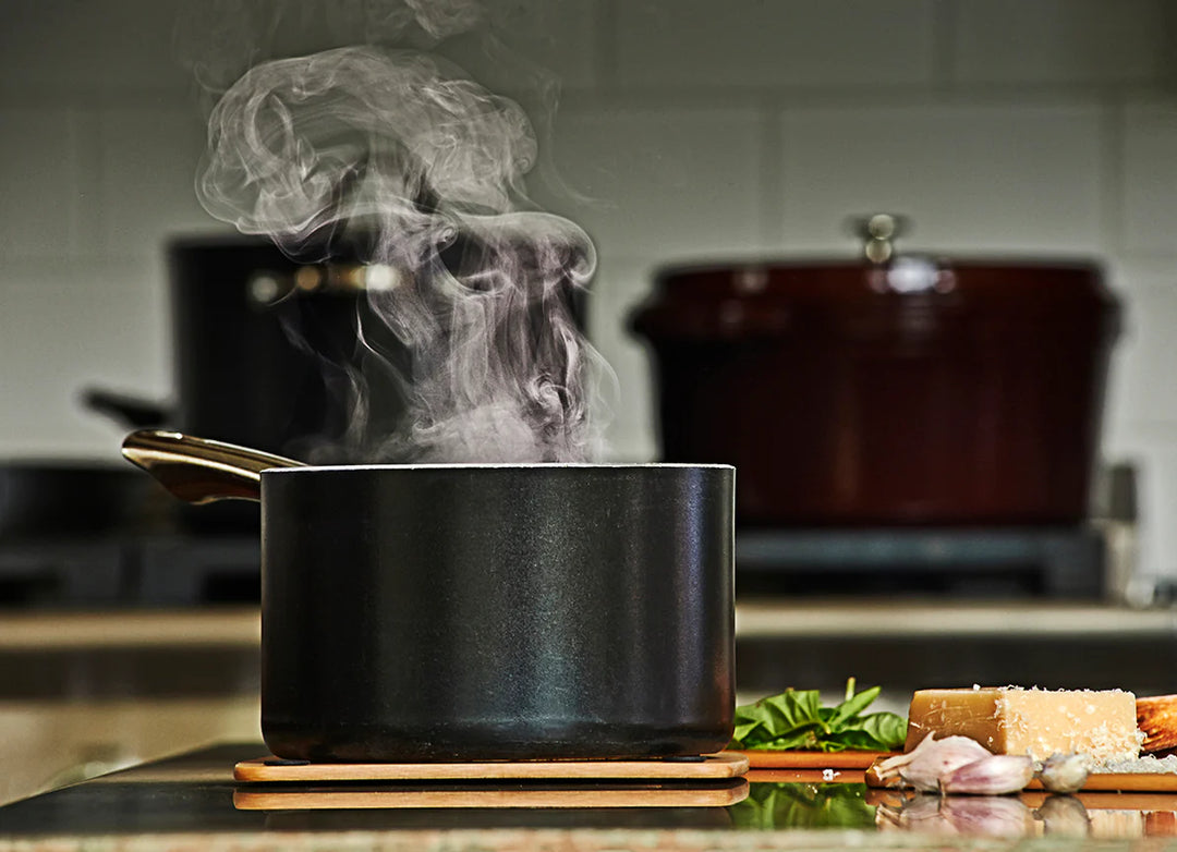 Steaming pot on a kitchen counter with ingredients and blurred background on a epicurean trivet