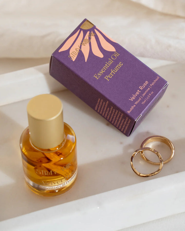 Essential oil perfume bottle with packaging and gold rings on a light background