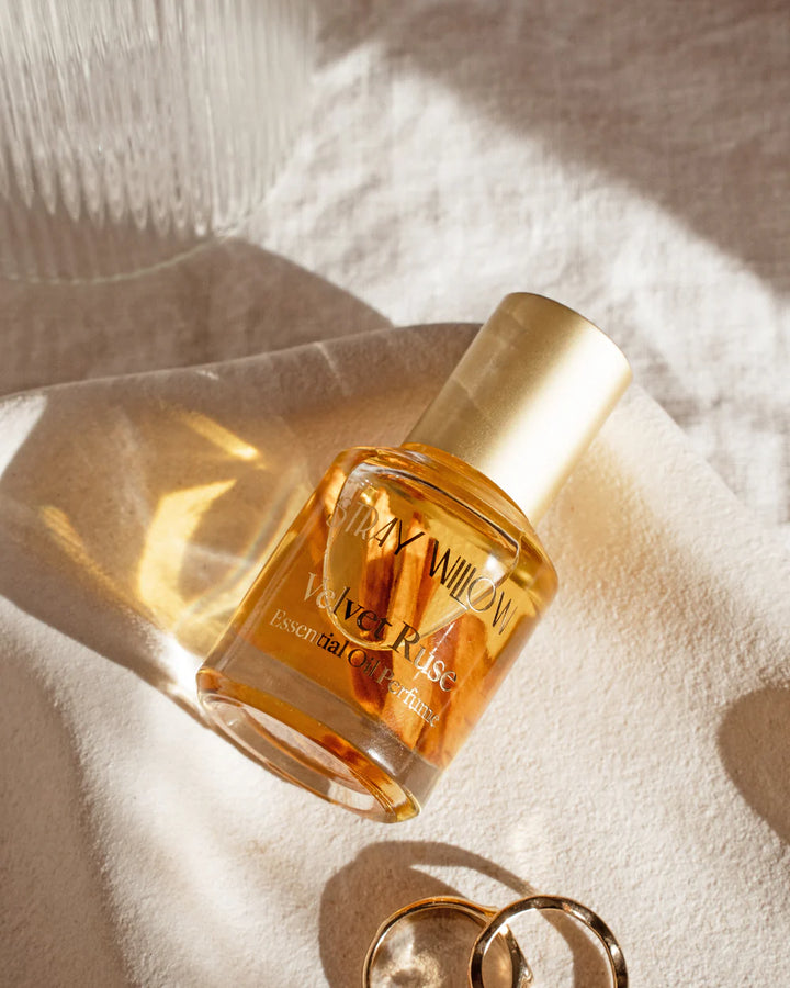 Perfume bottle labeled 'Velvet Ruse' on a textured surface with soft lighting