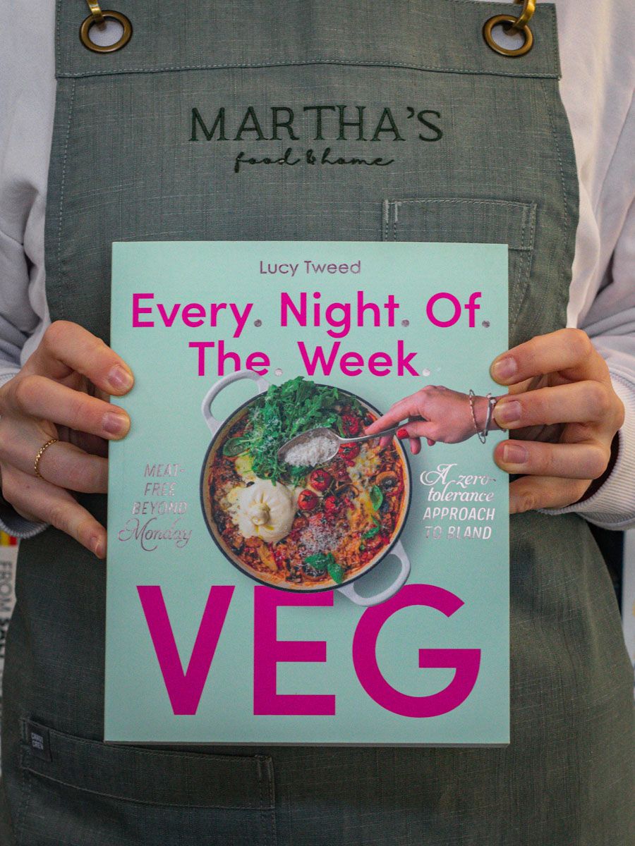 A person holding a book titled 'Every Night Of The Week Veg' by Lucy Tweed, with a green and pink cover featuring a photo of vegetables.