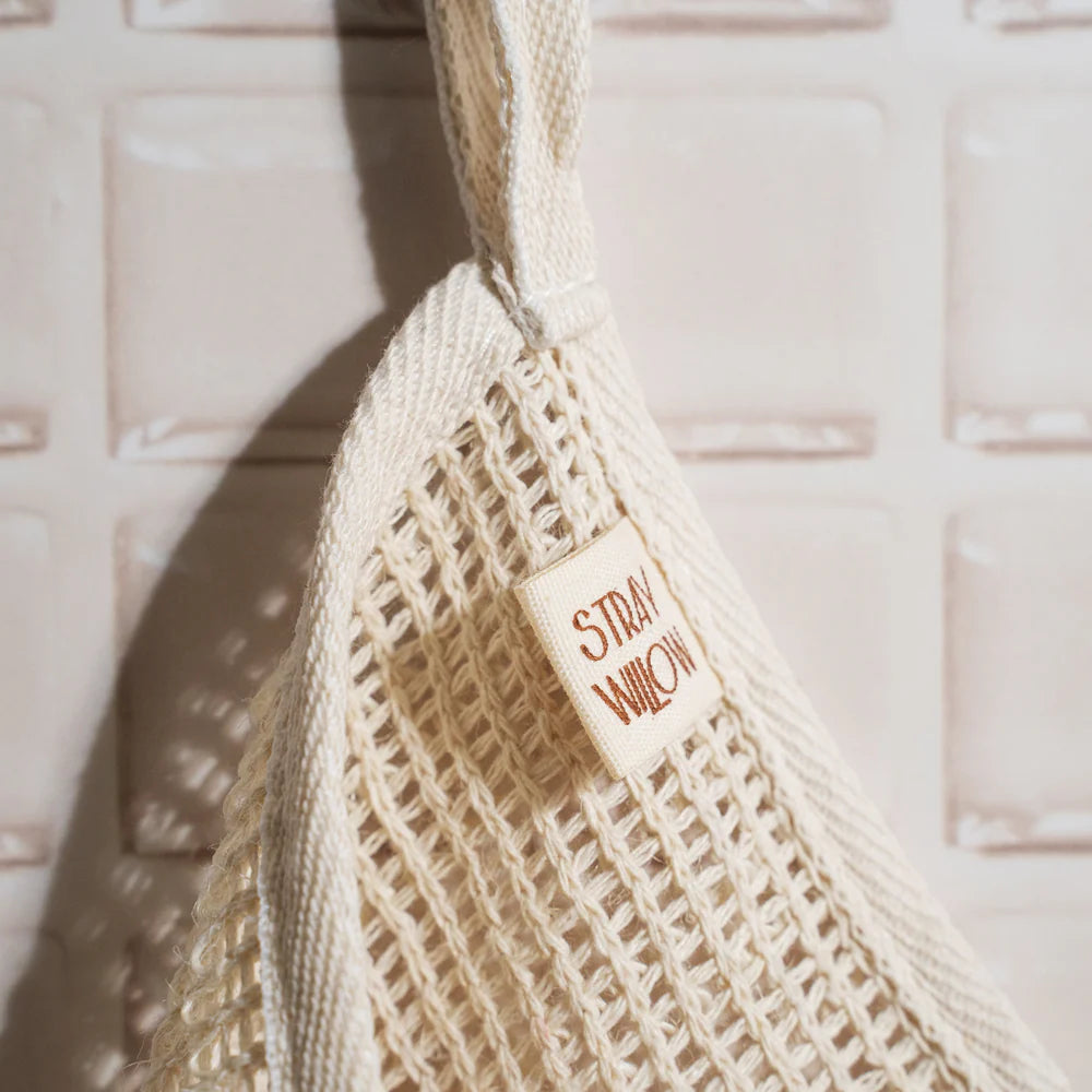 Beige exfoliating body cloth with 'Straw & Willow' label against a textured beige background