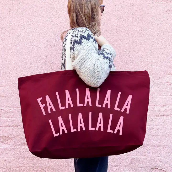 A woman viewed from behind carrying a large burgundy tote bag with pink text reading &