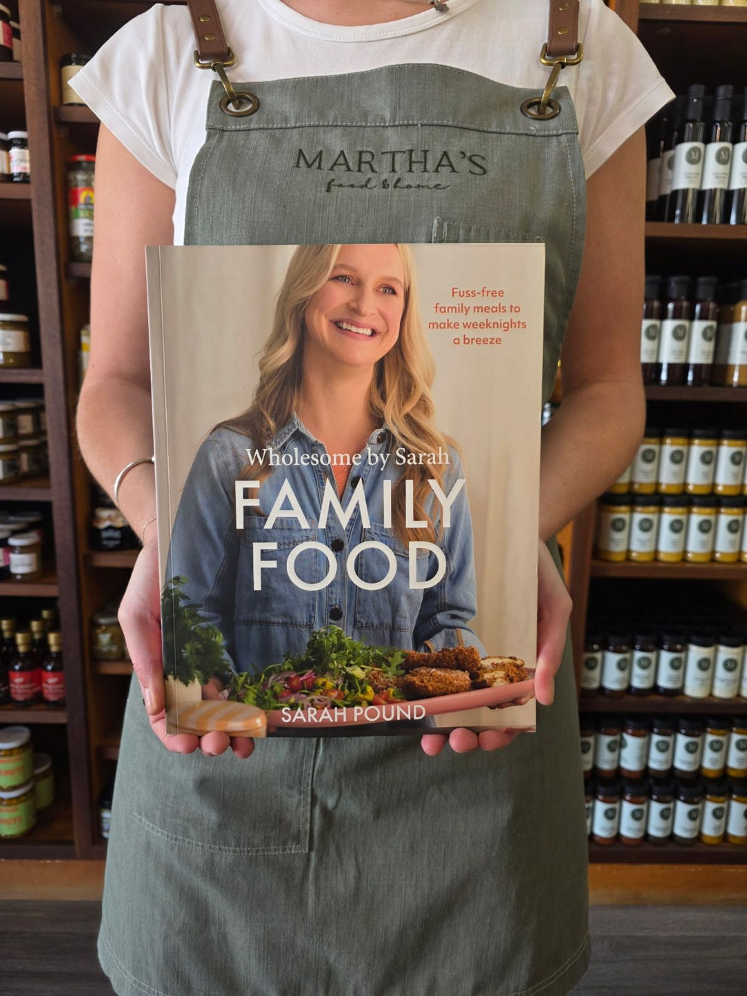 Person holding a cookbook titled 'Family Food' in a store setting