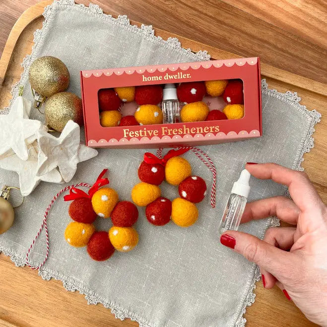 Festive fresheners with a hand holding a diffuser on a wooden surface.