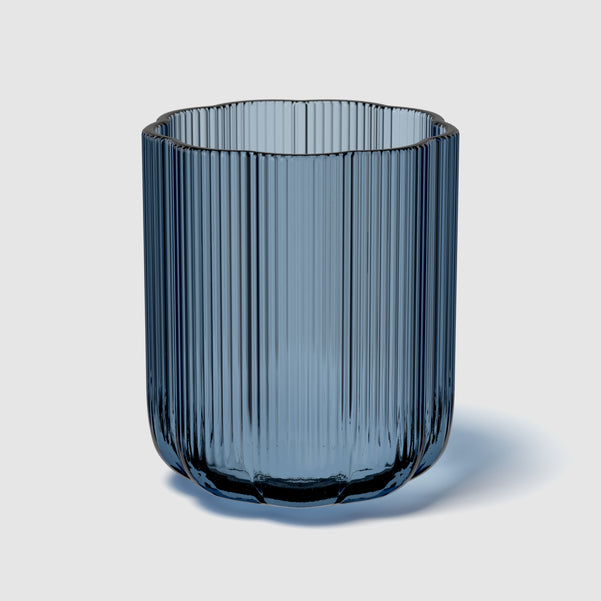 Blue glass vase with ribbed texture on a light gray background