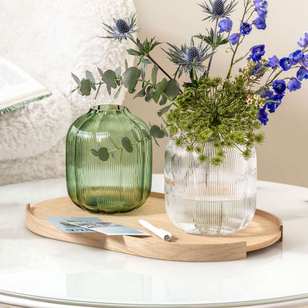 Two vases with flowers on a wooden tray on a table.