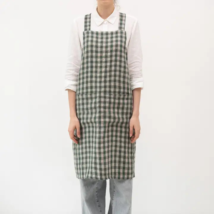 Person wearing a green and white checkered apron on a white background