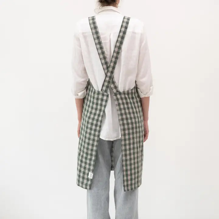 Person wearing a green and white checkered apron over a white shirt on a white background
