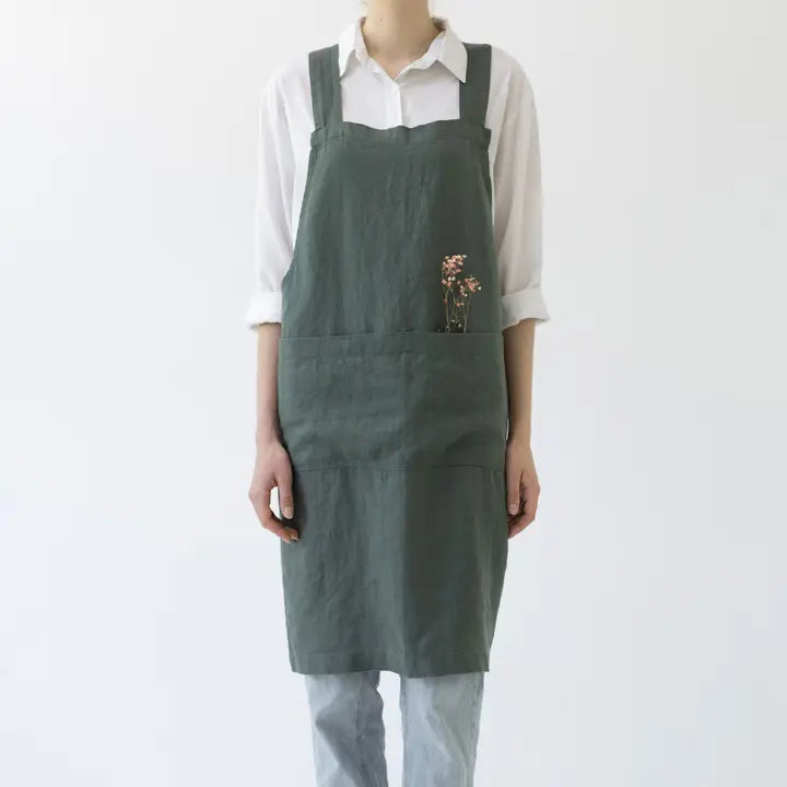 Person wearing a green apron with a white shirt underneath on a white background