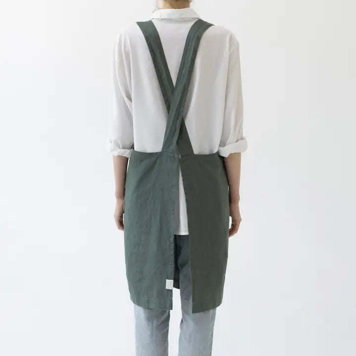 Person wearing a green apron over a white shirt on a white background