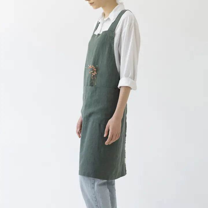 Person wearing a green apron with floral embroidery on a white background