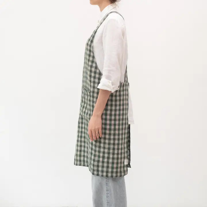 Person wearing a green and white checkered apron on a plain background