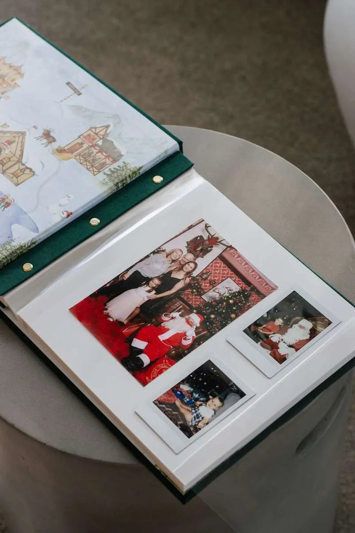Open photo album with Christmas-themed pages on a round surface.