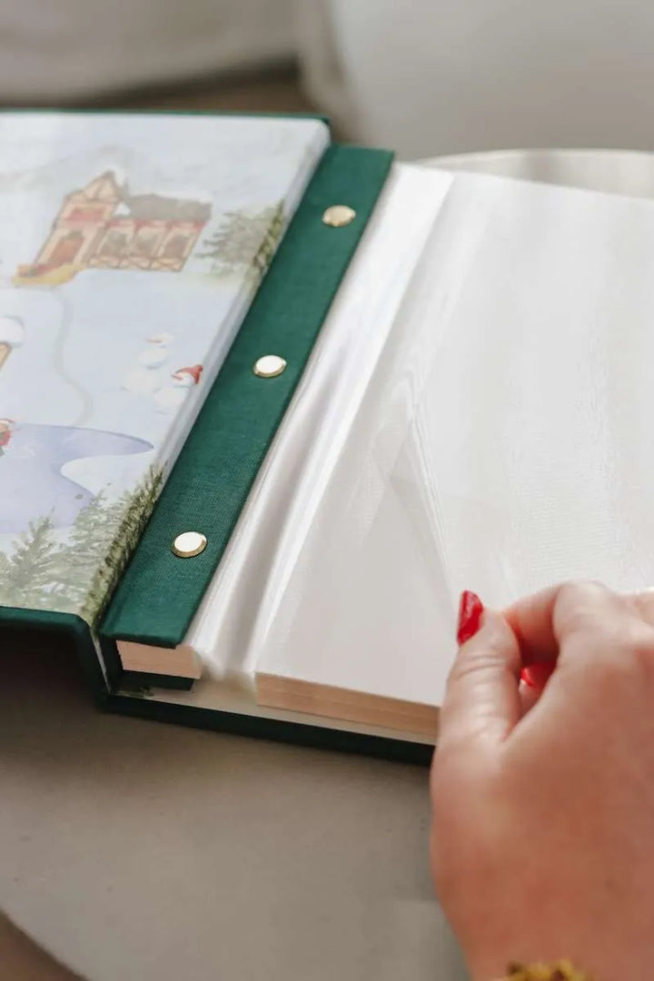 Hand holding a green-bound notebook with a decorative cover