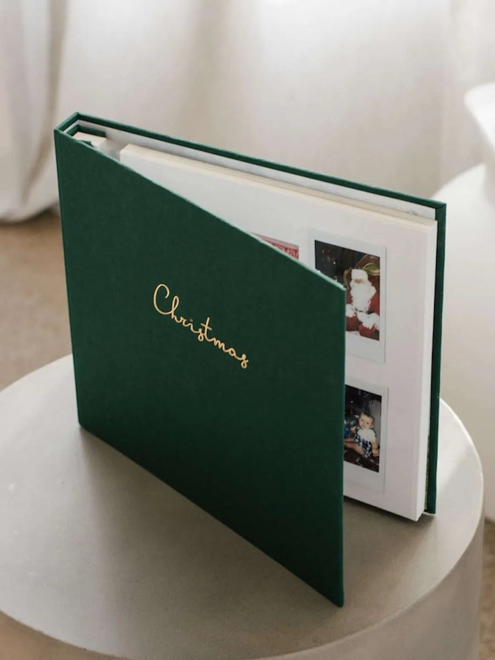 Green photo album with 'Christmas' on the cover, open to show photos inside.