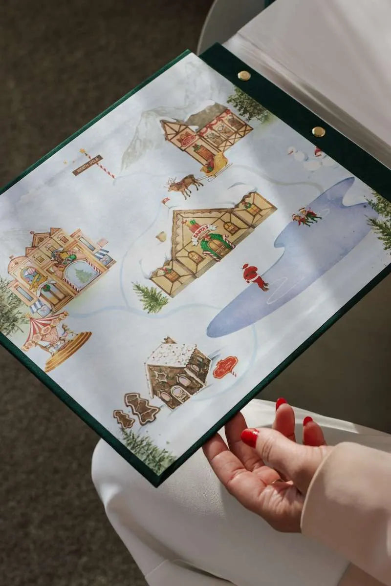 Hand holding a Christmas-themed advent calendar with gingerbread houses and Santa Claus.