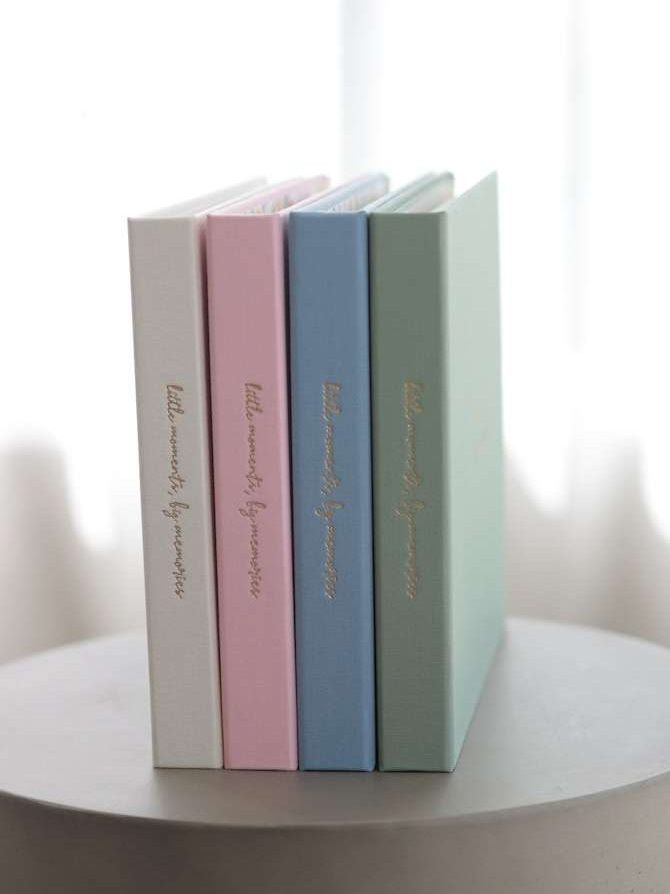 Four pastel-colored books stacked on a white surface with a light background