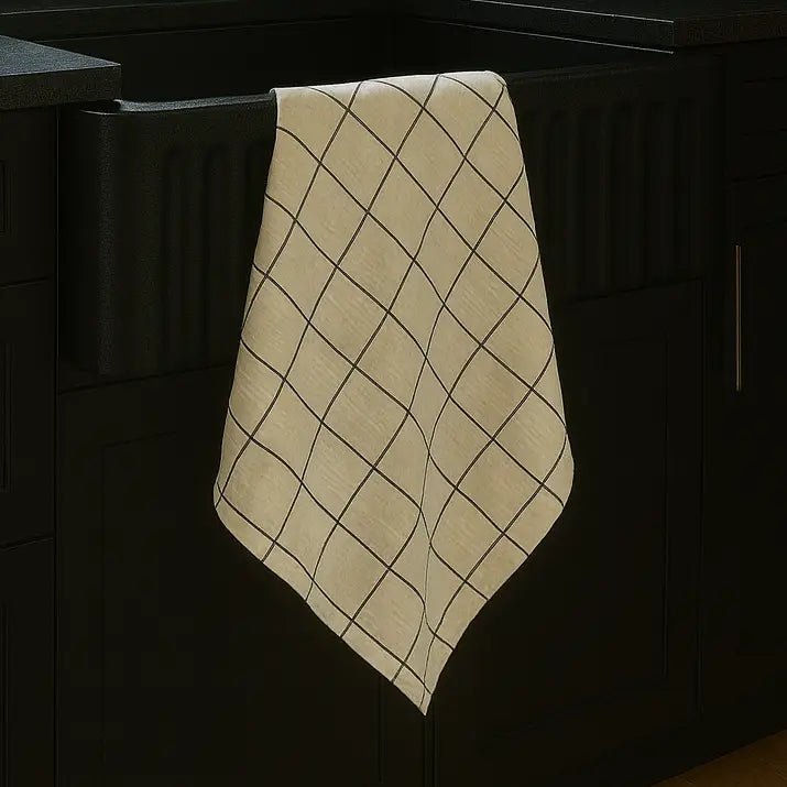 A beige kitchen towel with a black diamond grid pattern draped over a dark kitchen cabinet.