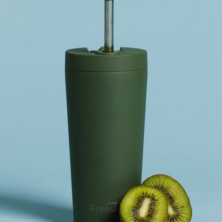 Green tumbler with a straw on a light blue background, featuring the brand &