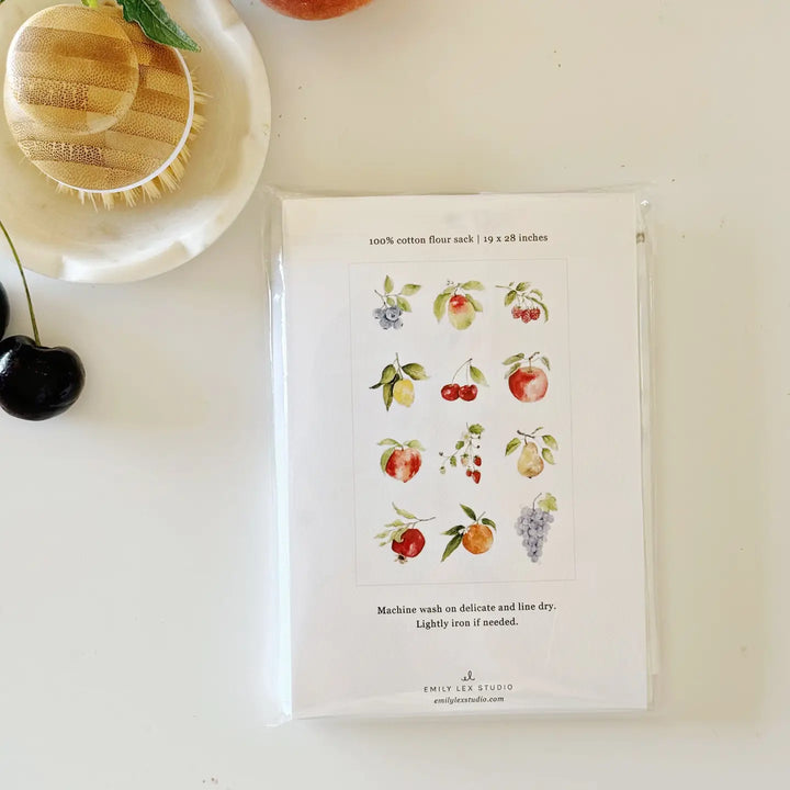 Tea towel in plastic packaging with fruit illustrations on a white surface