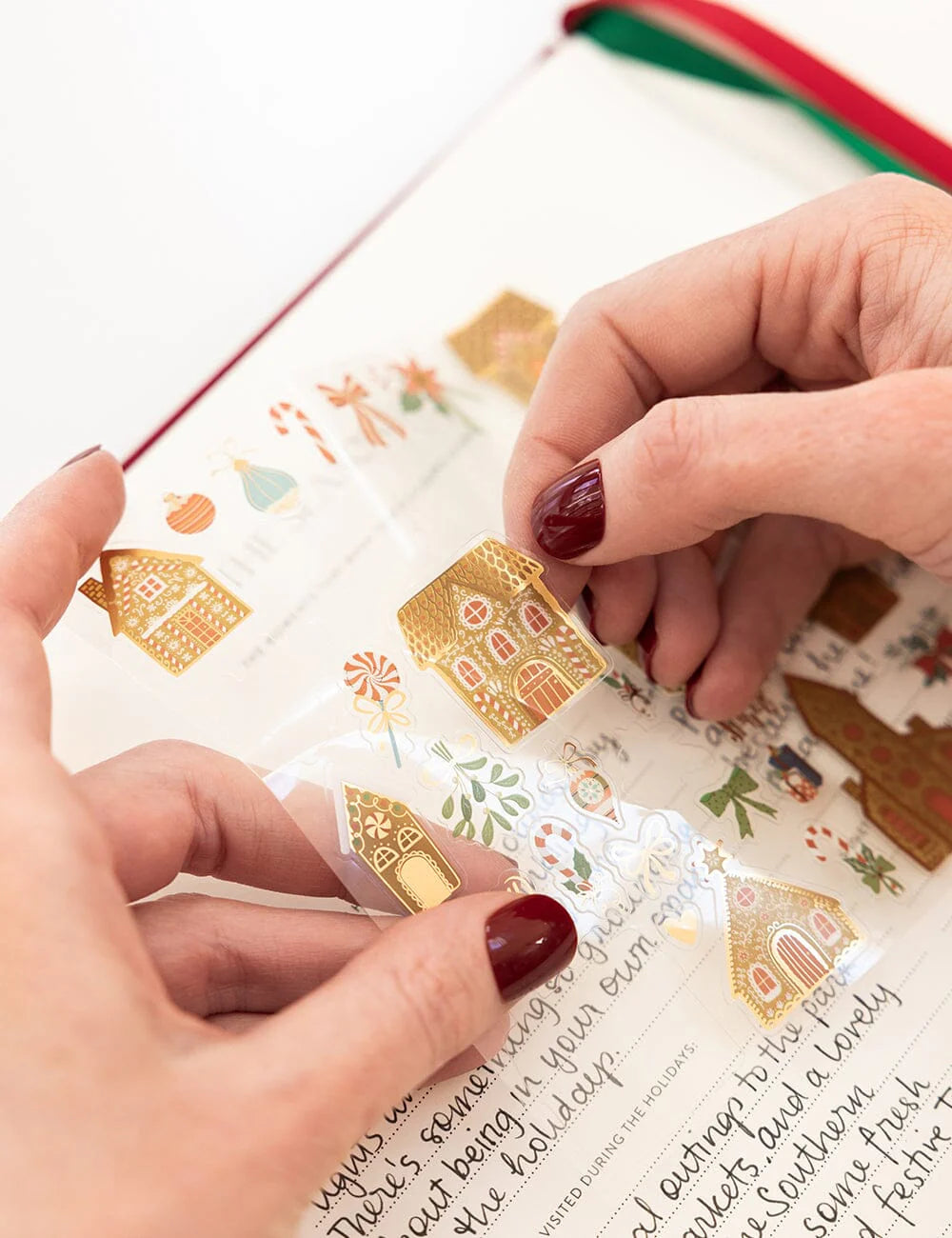 Person applying decorative gold stickers to a letter with festive designs.