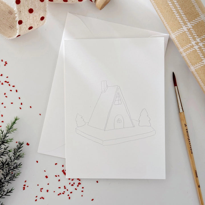 White card with a house illustration on a white surface with decorative items.