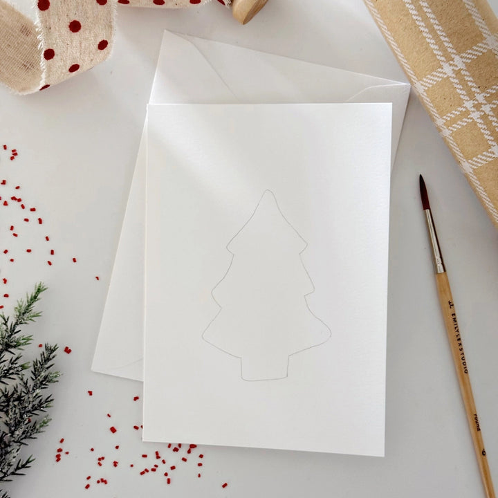 White card with tree cutout on a white surface with decorative items.