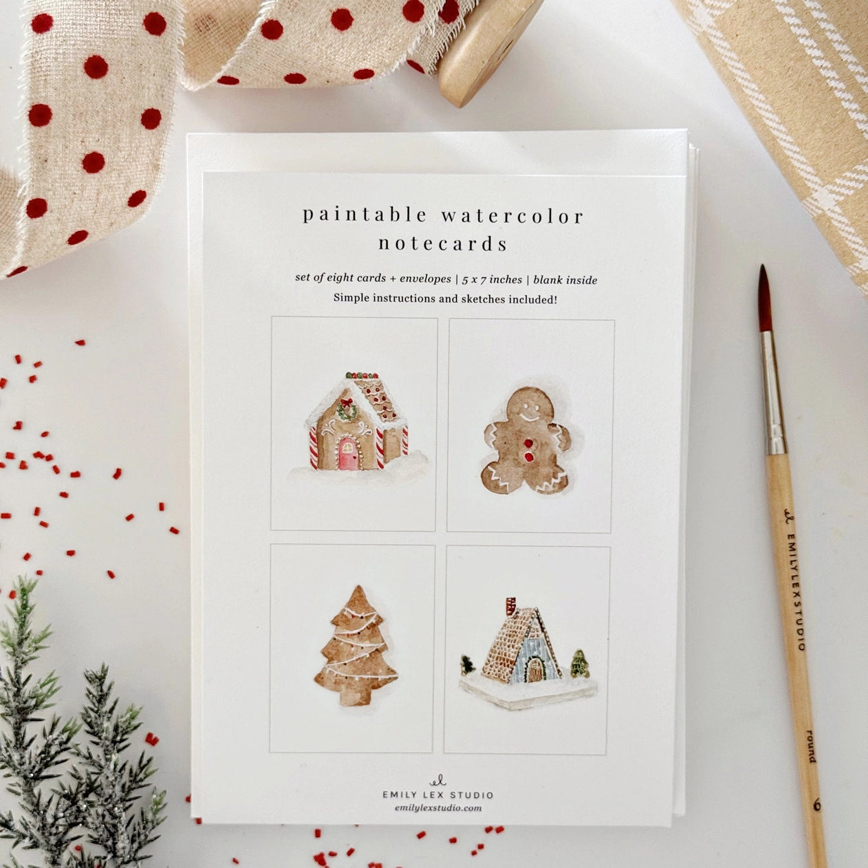 Set of paintable watercolor notecards with Christmas-themed designs on a white surface.