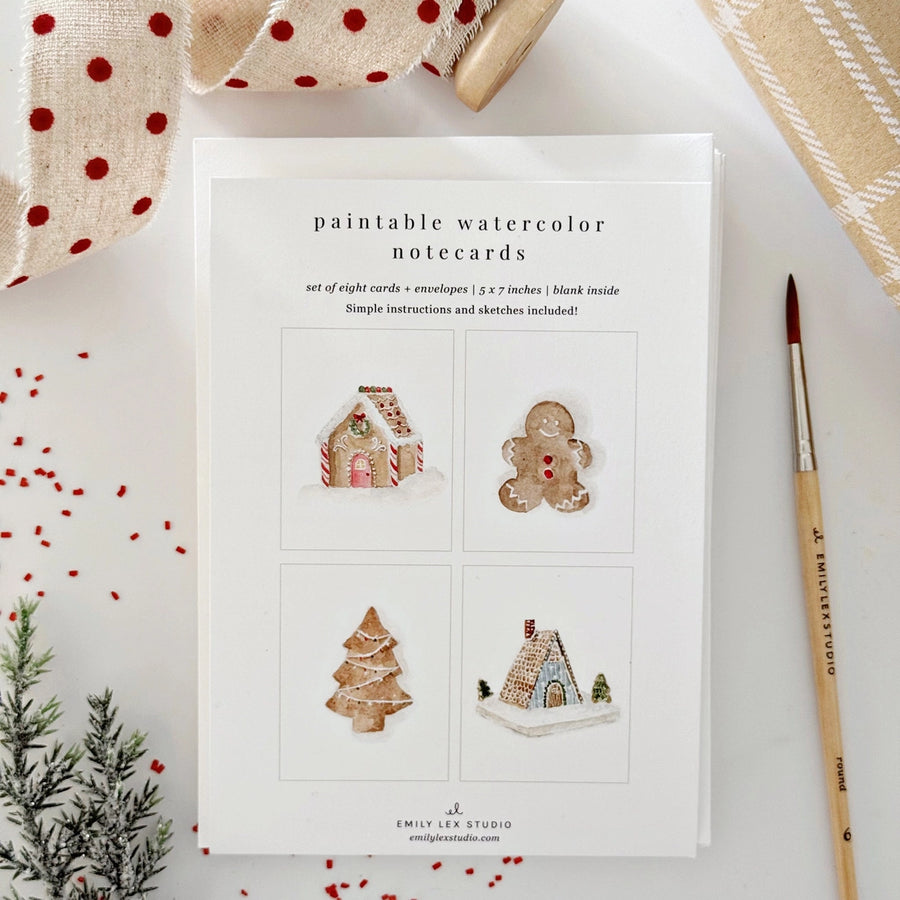 Set of paintable watercolor notecards with Christmas-themed designs on a white surface.