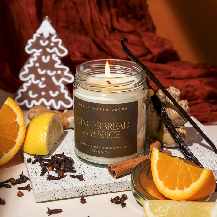 Gingerbread and Spice candle with cinnamon sticks, oranges, and cloves on a decorative surface.