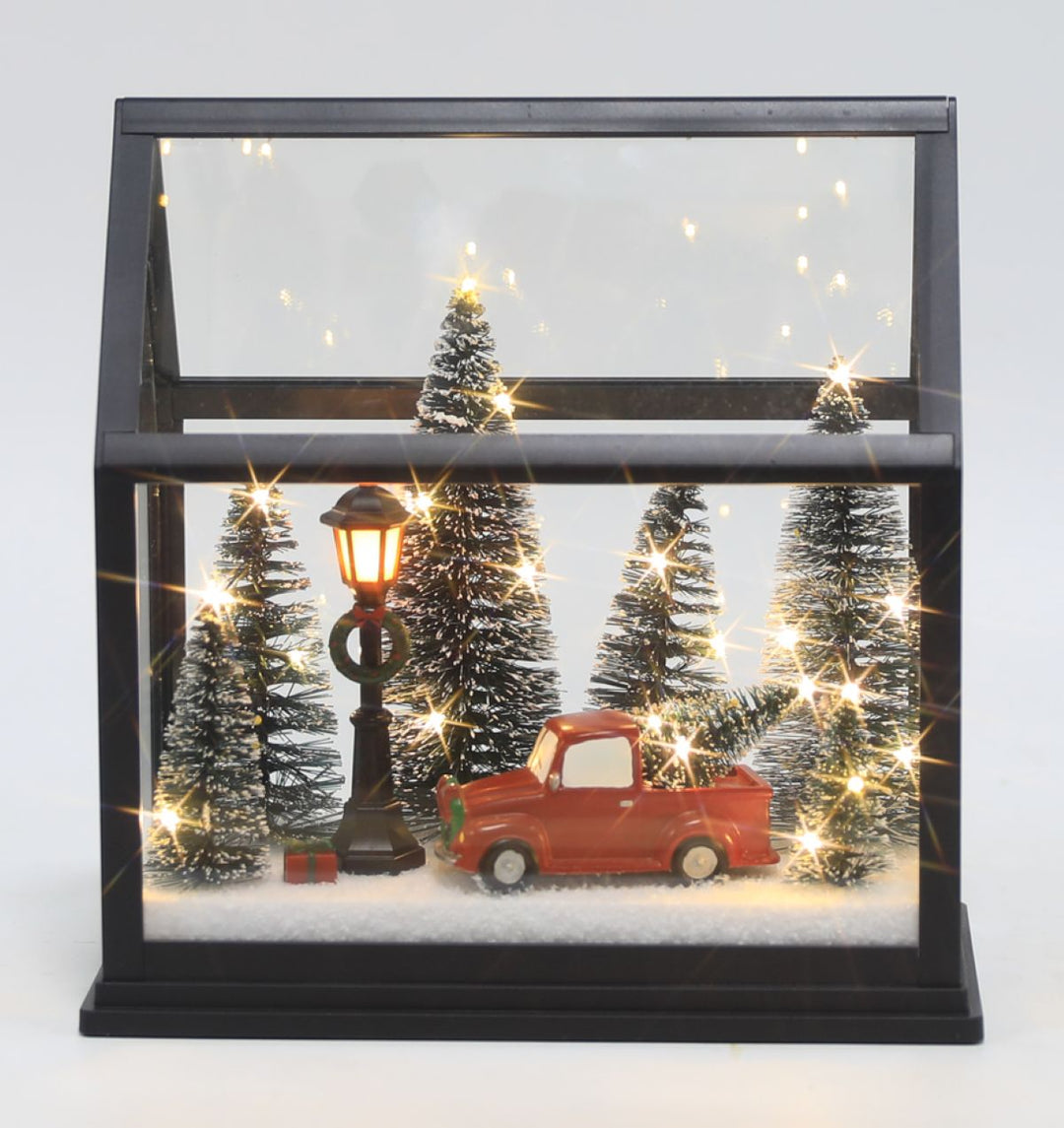 A Christmas glass light up lantern with Christmas trees, a red truck &amp; lamp post. 