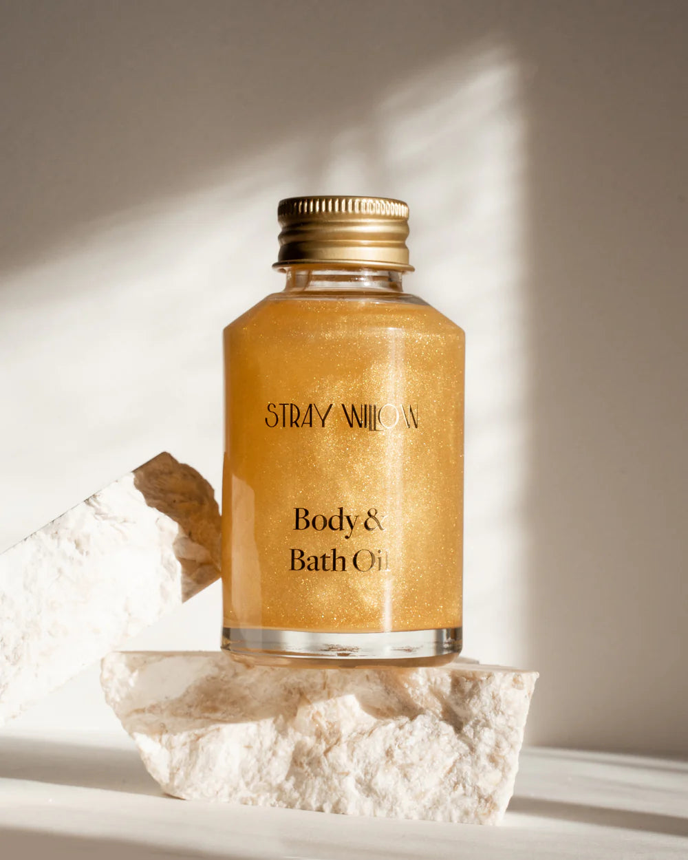 Stray Willow body and bath oil bottle on a stone surface with soft lighting
