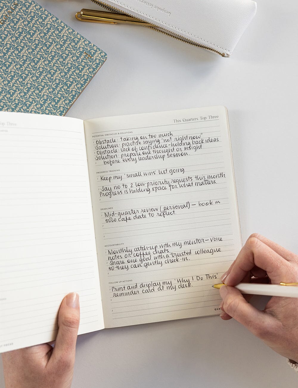 Person writing in a notebook with a pen on a light surface