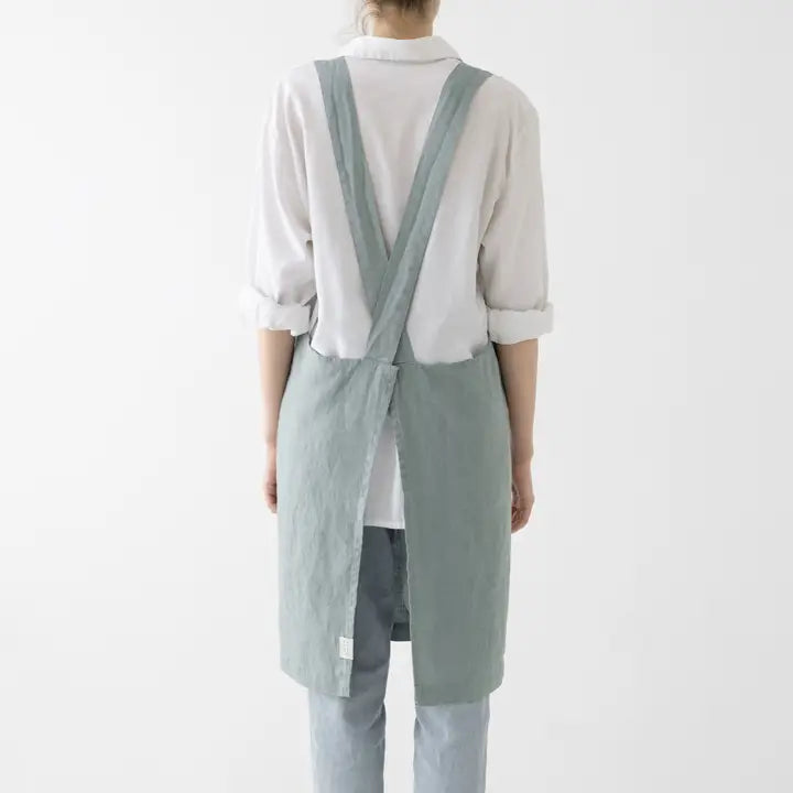 Person wearing a light green apron over a white shirt on a white background