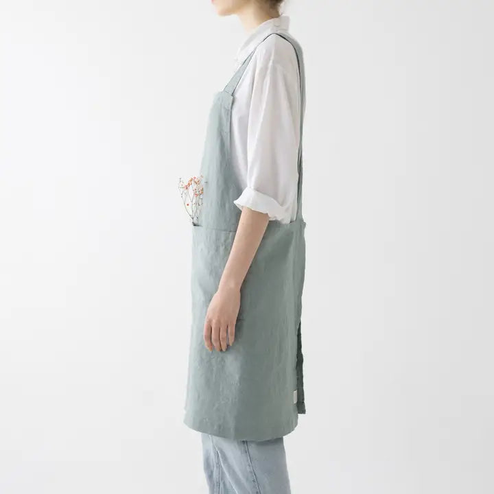 Person wearing a light green apron over a white shirt on a plain background