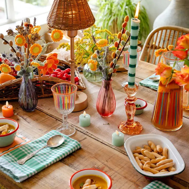 Decorative table setting with flowers, candles, and food on a wooden table.