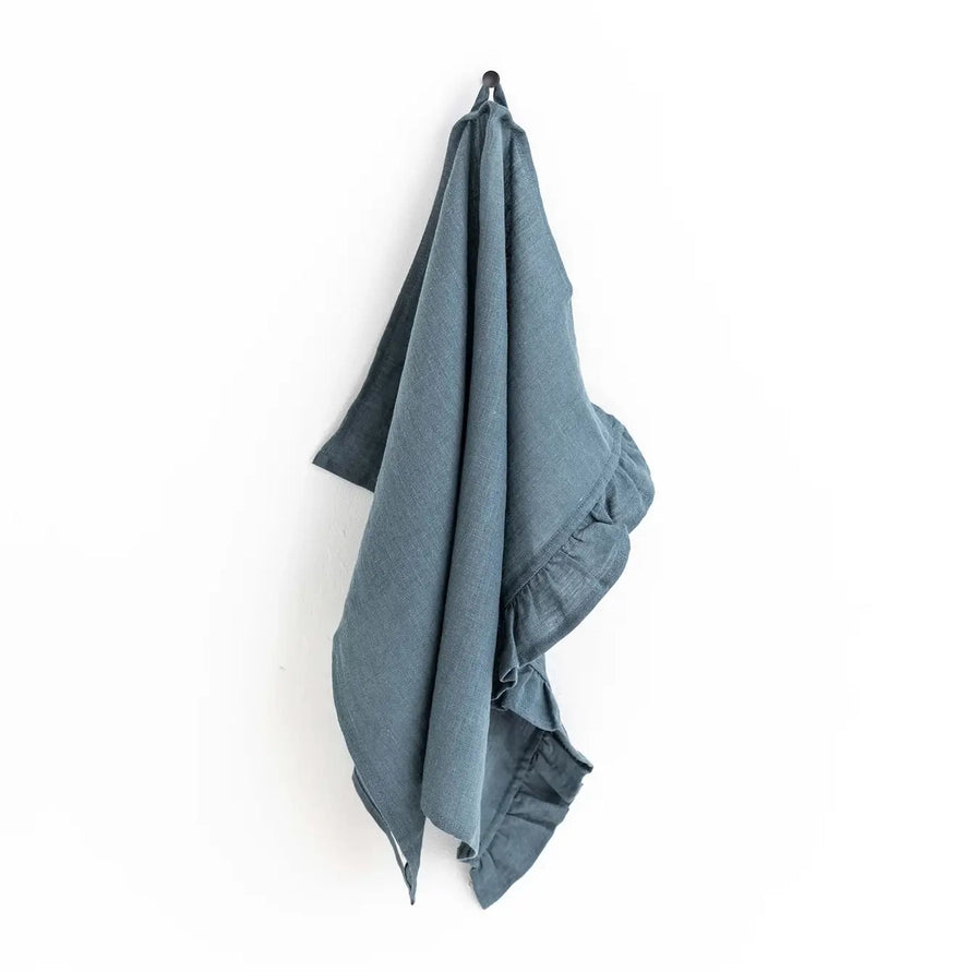 Blue towel hanging on a hook against a white background