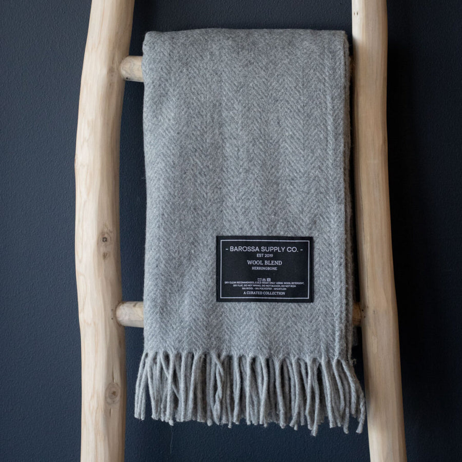 Gray wool blanket with a label on a wooden ladder against a dark background