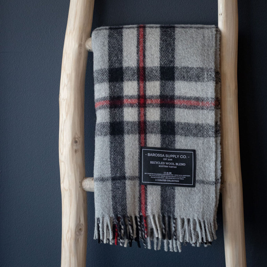 Plaid blanket with a label on a wooden ladder against a dark wall