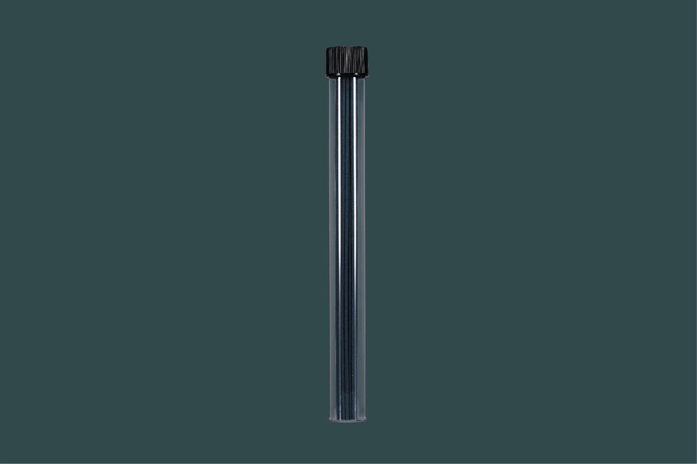 Clear cylindrical container with incense sticks with black cap on a dark gray background