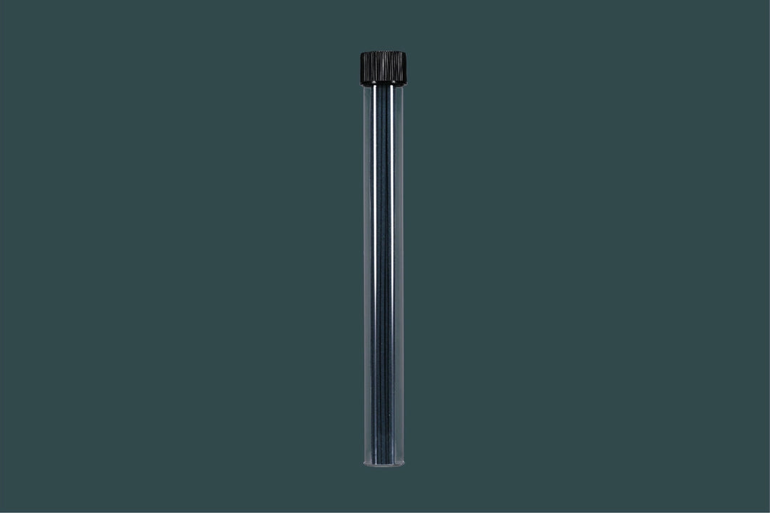 Clear cylindrical container with incense sticks with black cap on a dark gray background