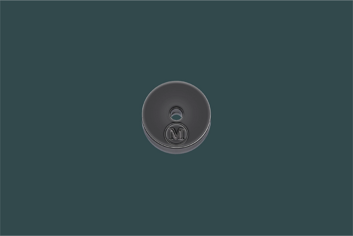 Round metallic button with a logo on a dark green background