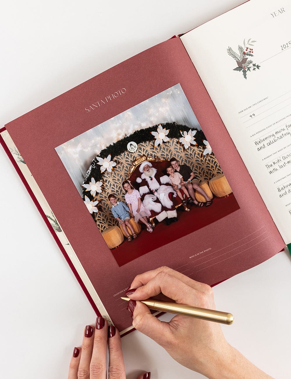 Person signing a red album with a gold pen on a white surface