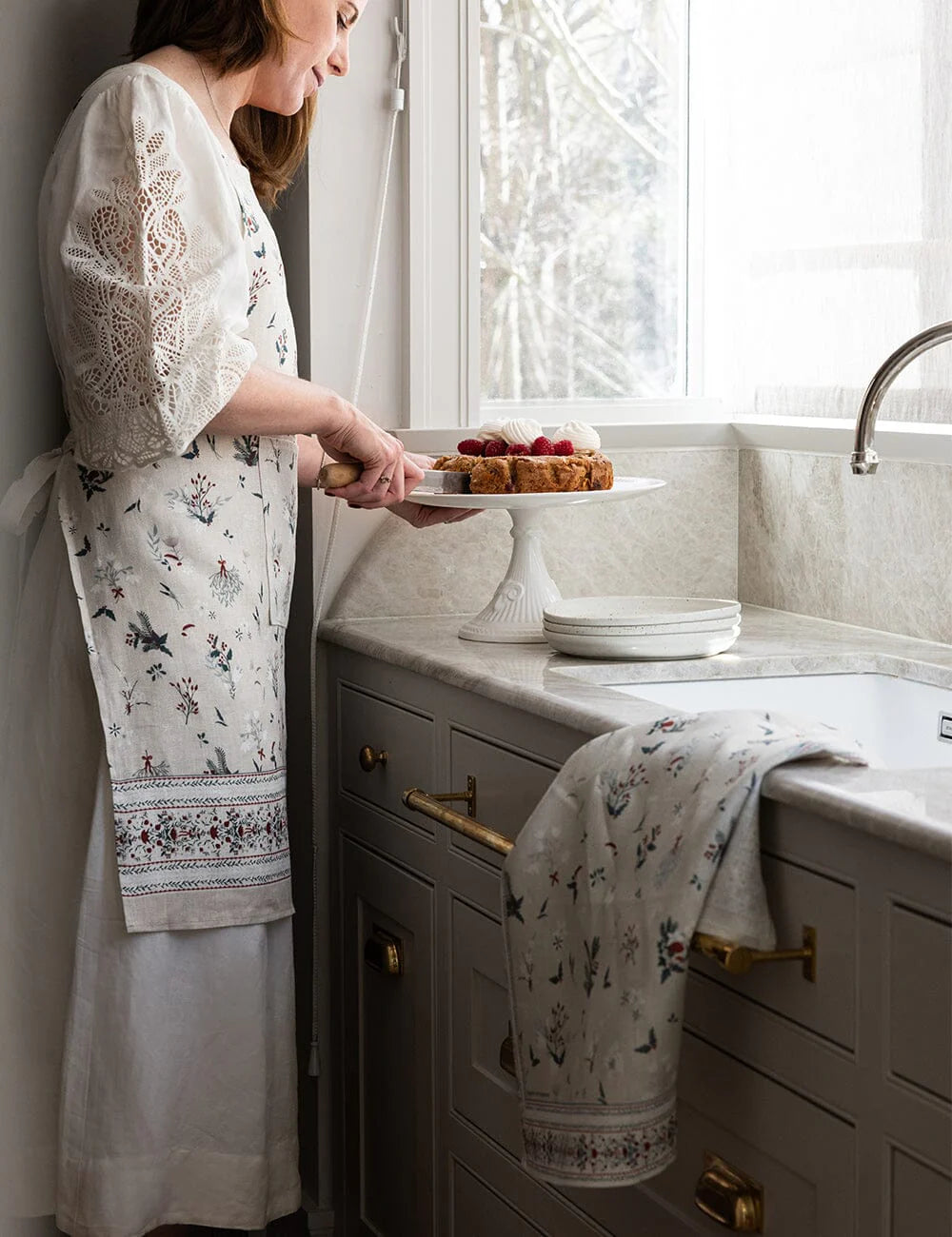 Someone wearing a christmas apron with matching tea towel on the kitchen bench