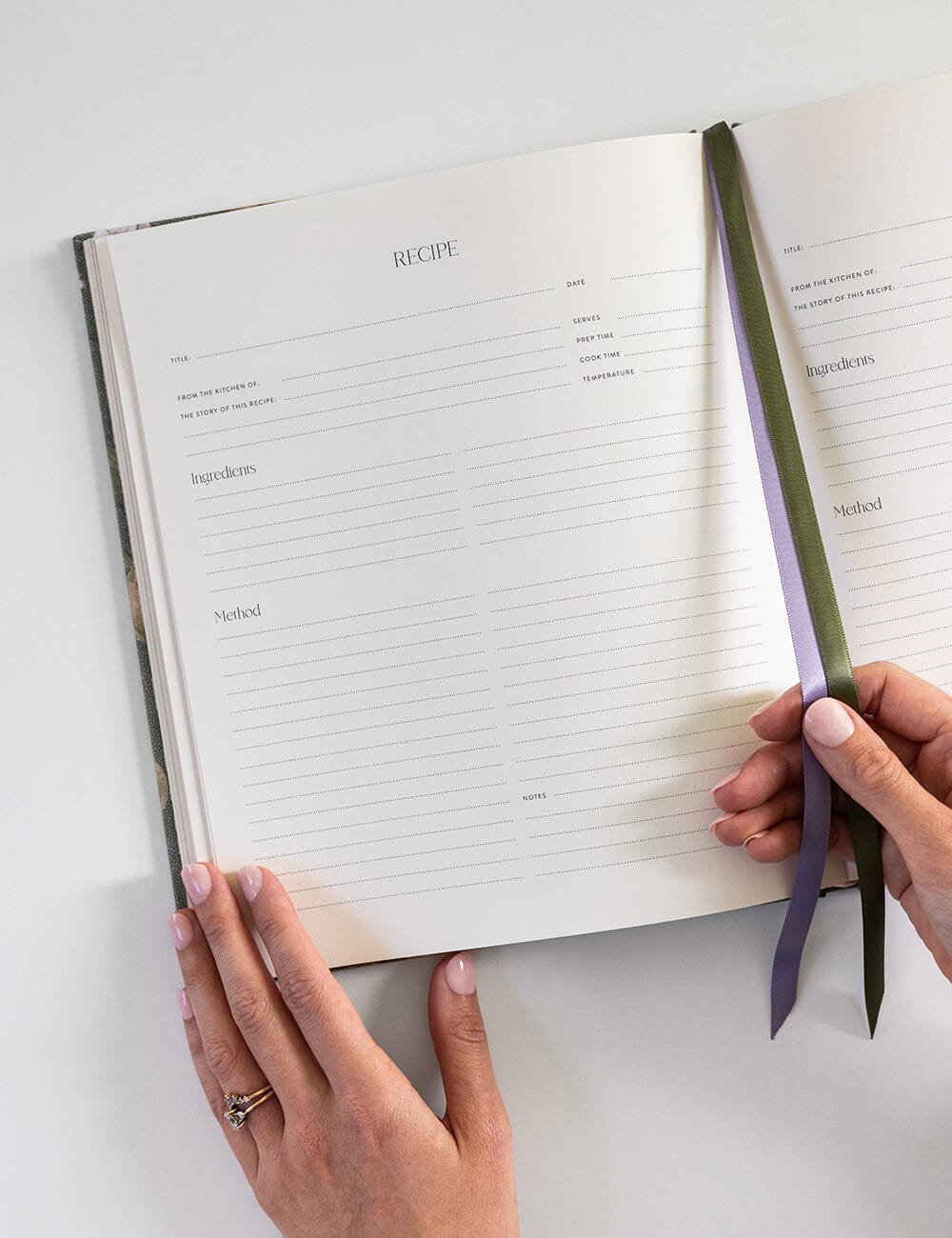 Open recipe book with a hand holding a green pen on a white surface