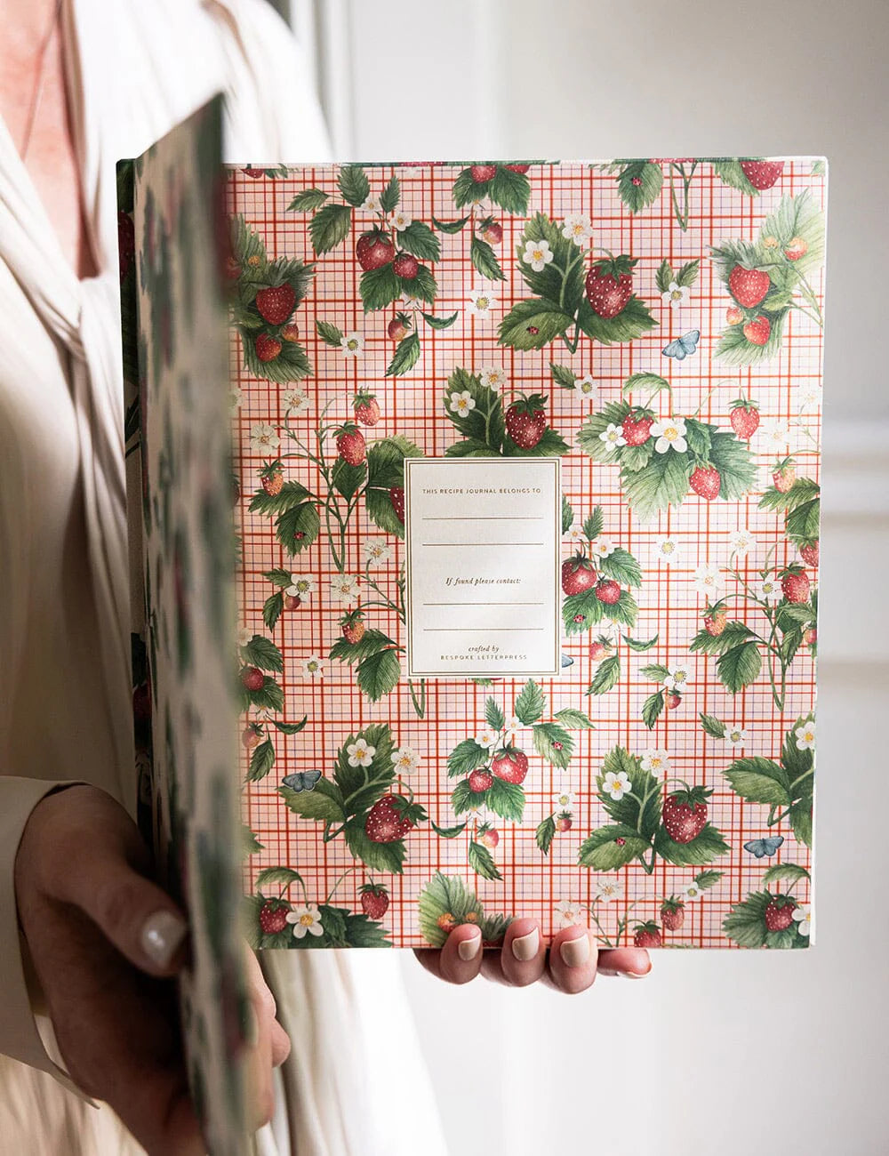 Person holding a notebook with a floral and checkered design