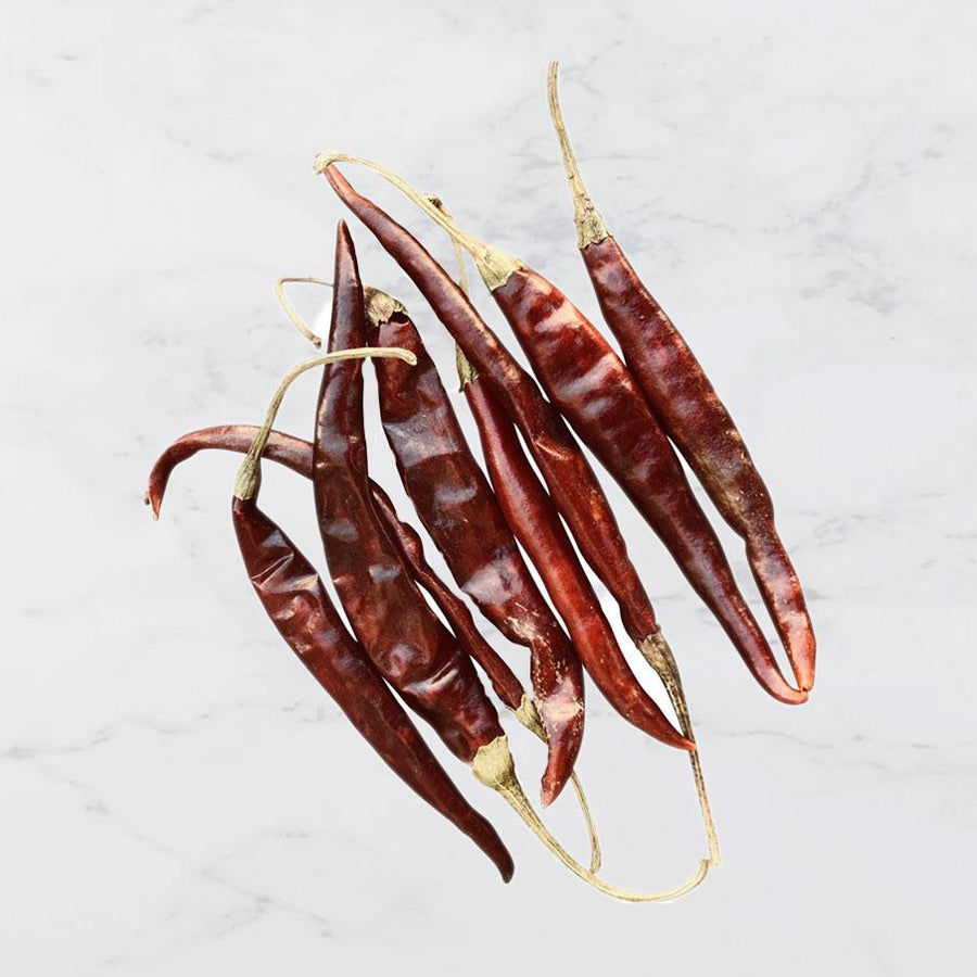 Dried red chili peppers on a light gray background