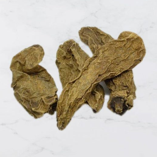 Three dried chipotle chillies on a light gray background