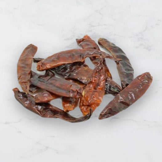 Dried red chilies on a light gray background
