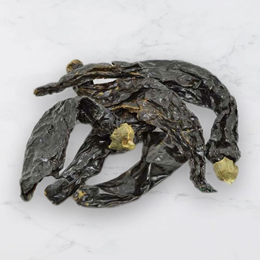 Dried pasilla chillies on a white background